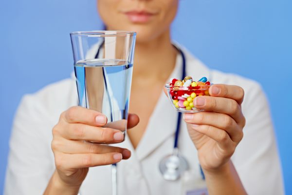 врач с таблетками и стаканом воды